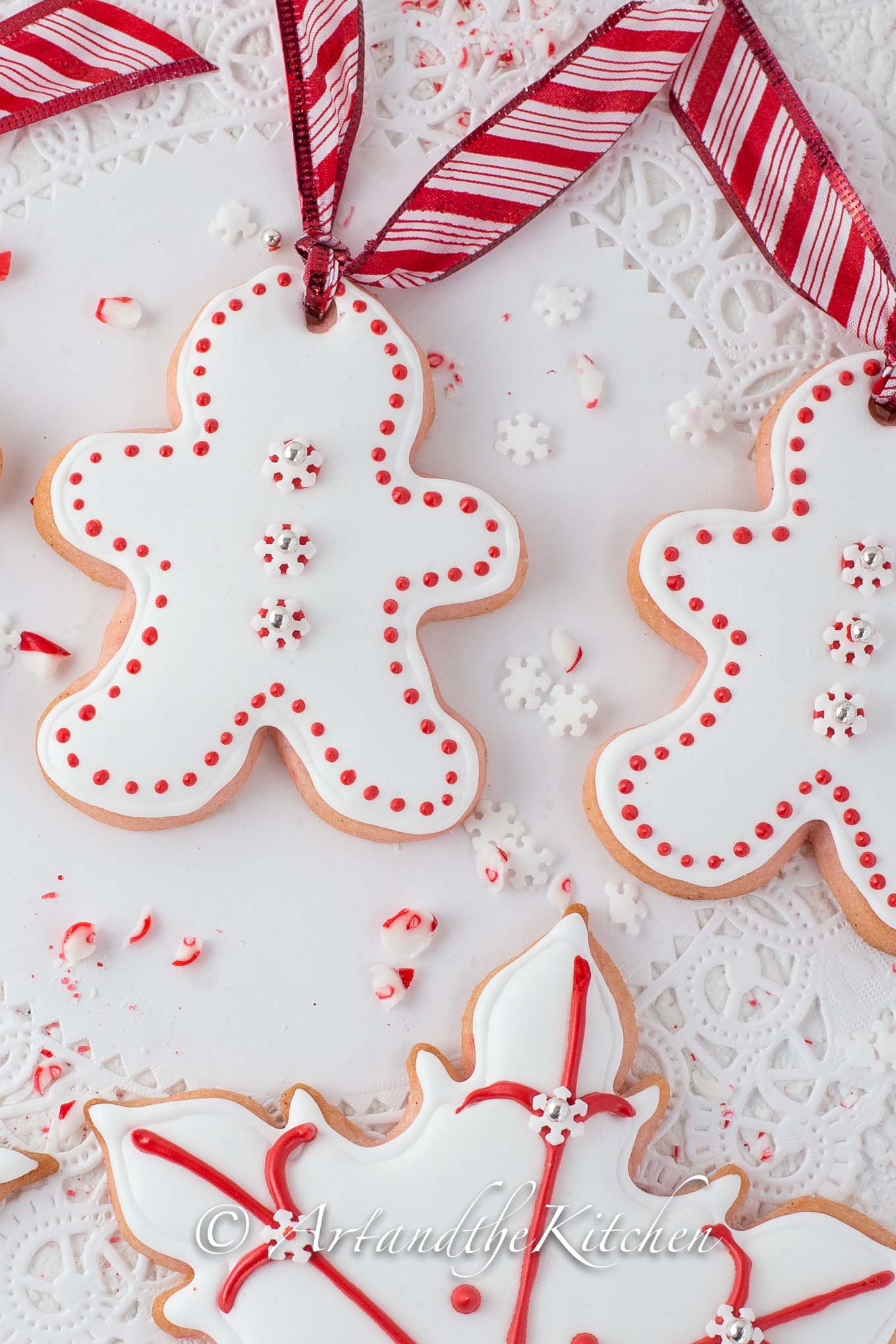 Sugar cookies cut into gingerbread men shapes, coated with white royal icing and decorated with red dots.