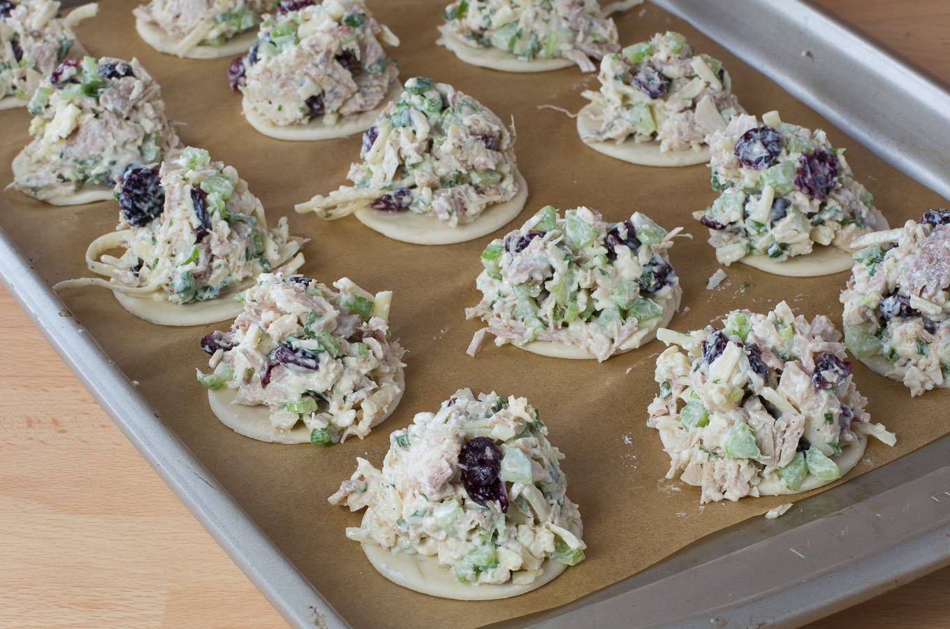 Bites of puffed pastry topped with turkey salad mix and cranberries.