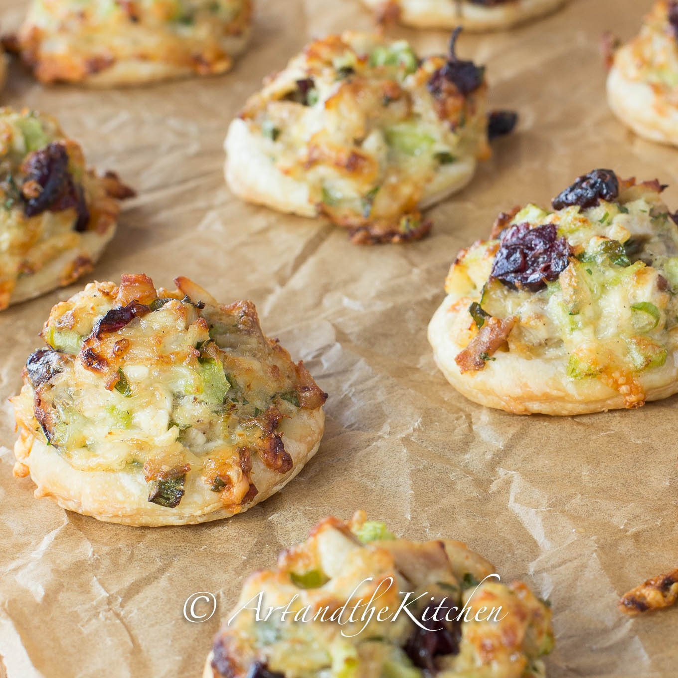 Bites of puffed pastry topped with turkey salad mix and cranberries.