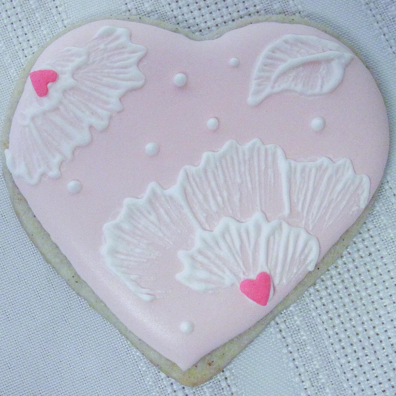 Heart shaped sugar cookie decorated with pink icing.