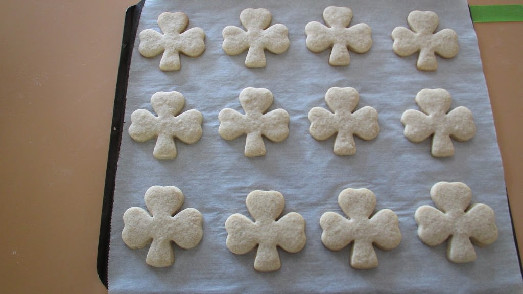 Baked Shamrock shaped cookies on parchment lined baking sheet.