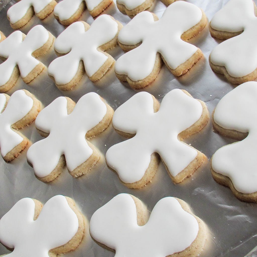 Foiled lined baking sheet filled with cookies coated with white royal icing.