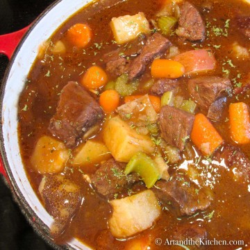 Pot of Irish beef stew with carrots, potatoes, celery in brown gravy.