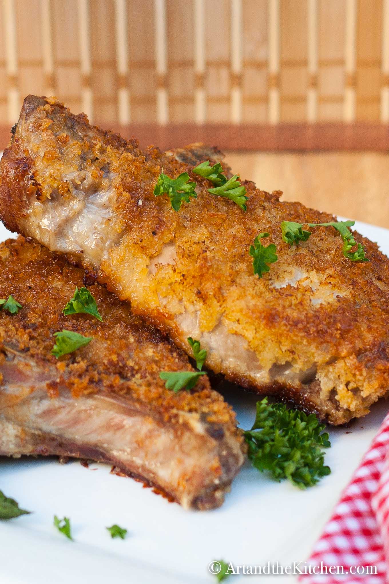 Two breaded pork chops fried golden brown on white plate.