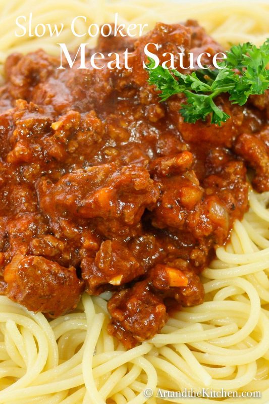 Thick meat sauce on spaghetti pasta with parsley sprig.