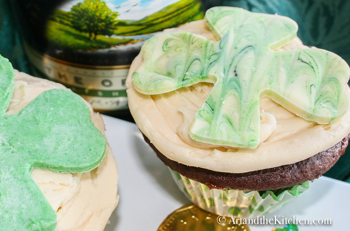 two chocolate cupcakes decorated for St. Patrick's Day on a plate