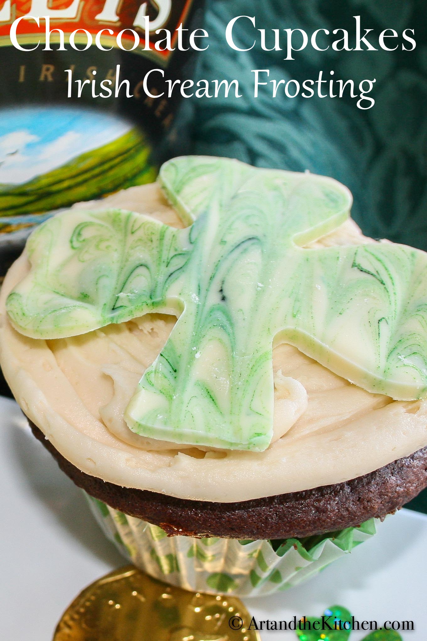 chocolate cupcake topped with a white chocolate shamrock. Baileys Irish cream bottle in background.