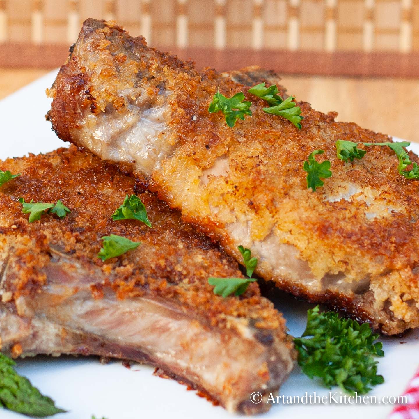 Two breaded pork chops fried golden brown on white plate.