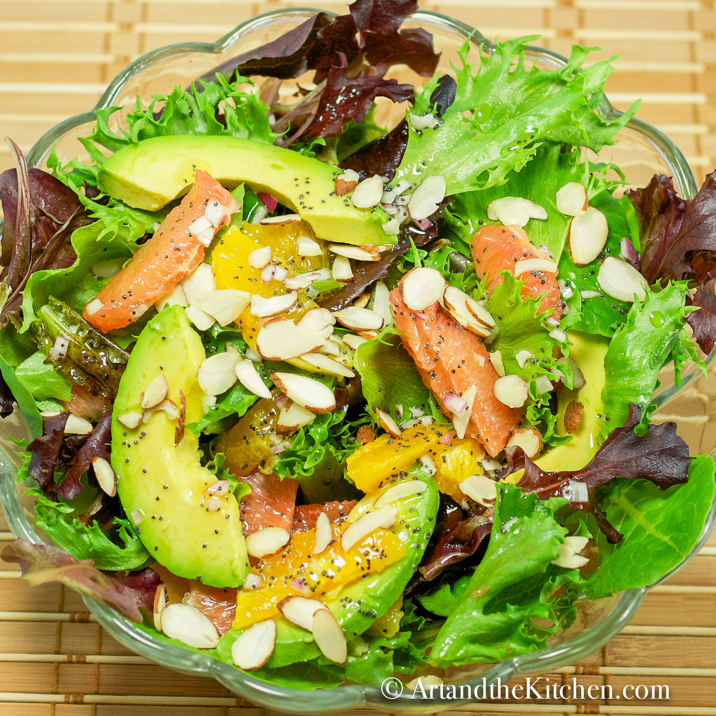 A bowl of fresh salad greens with avocado, grapefruit, and oranges. Sprinkled with almond slivers and poppyseed dressing.
