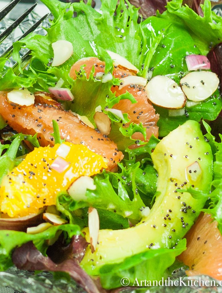A bowl of fresh salad greens with avocado, grapefruit, and oranges. Sprinkled with almond slivers and poppyseed dressing.
