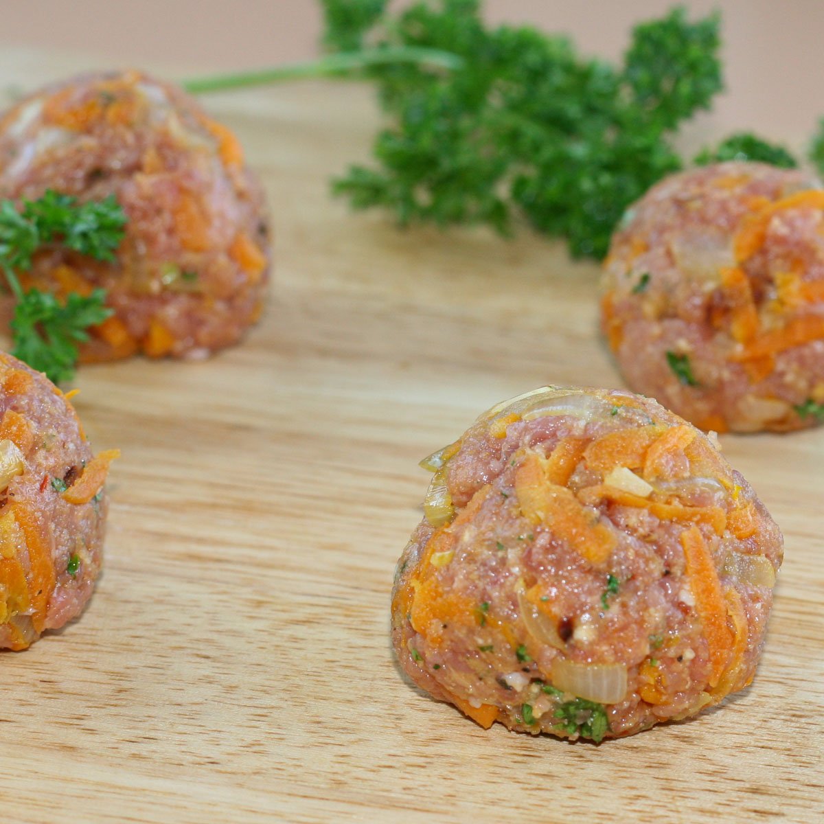 Uncooked meatballs made with on wood board.