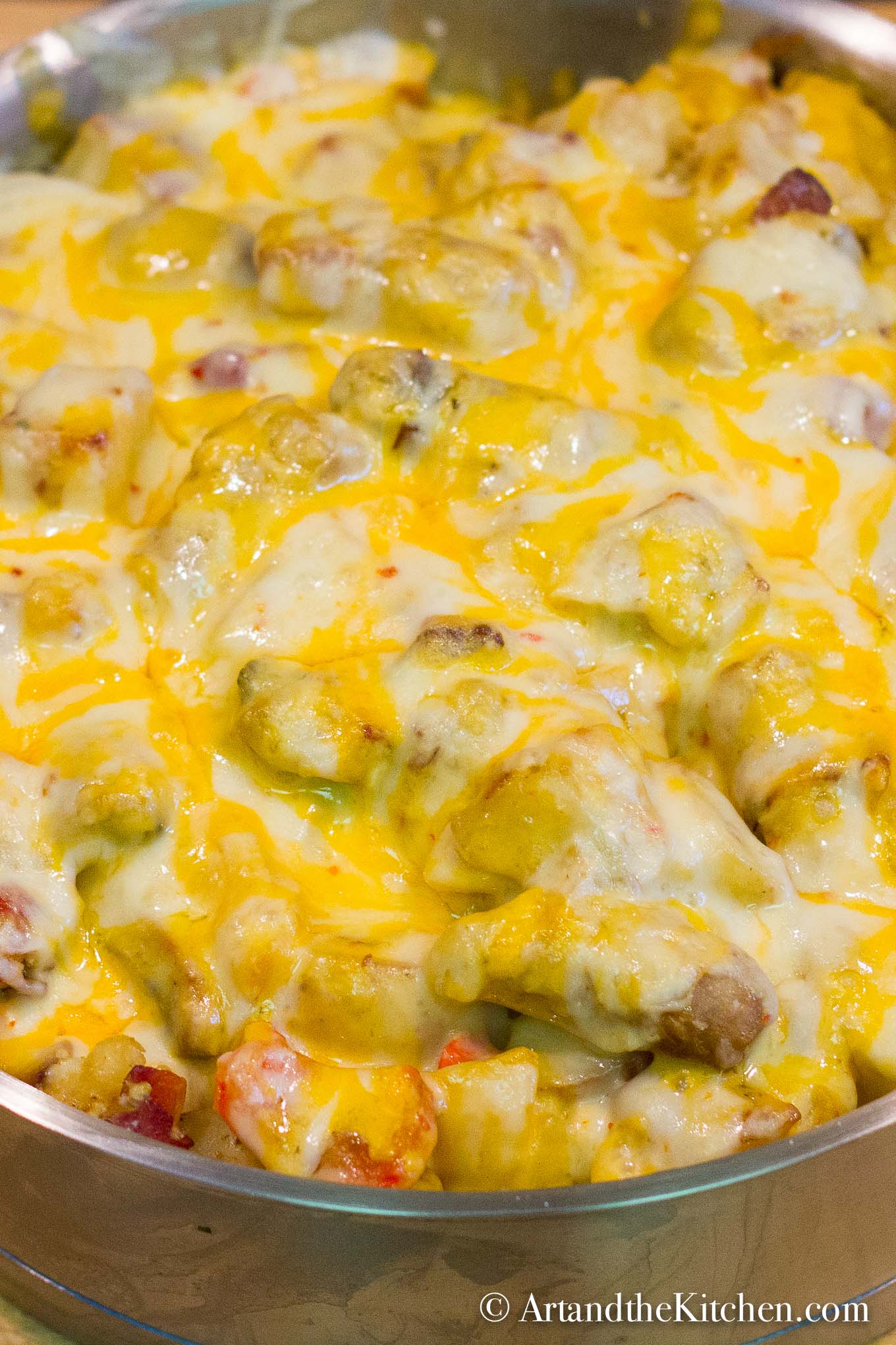 A hearty skillet of sausage, eggs and vegetables, topped with melted cheese. Served in a stainless steel skillet.