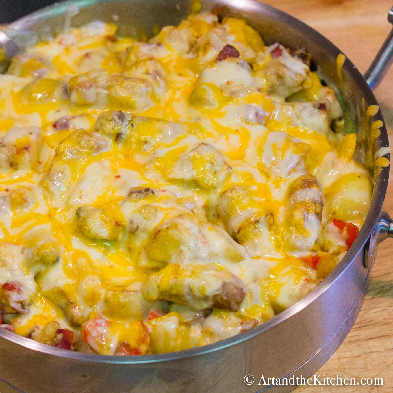 A hearty skillet of sausage, eggs and vegetables, topped with melted cheese. Served in a stainless steel skillet.