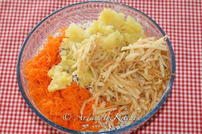 Shredded carrots, apple and well drained crushed pineapple in glass bowl on red checkered cloth.