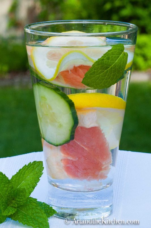 Glass of water with slices of grapefruit, cucumber, lemon and mint.