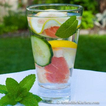 Glass of water with slices of grapefruit, cucumber, lemon and mint.