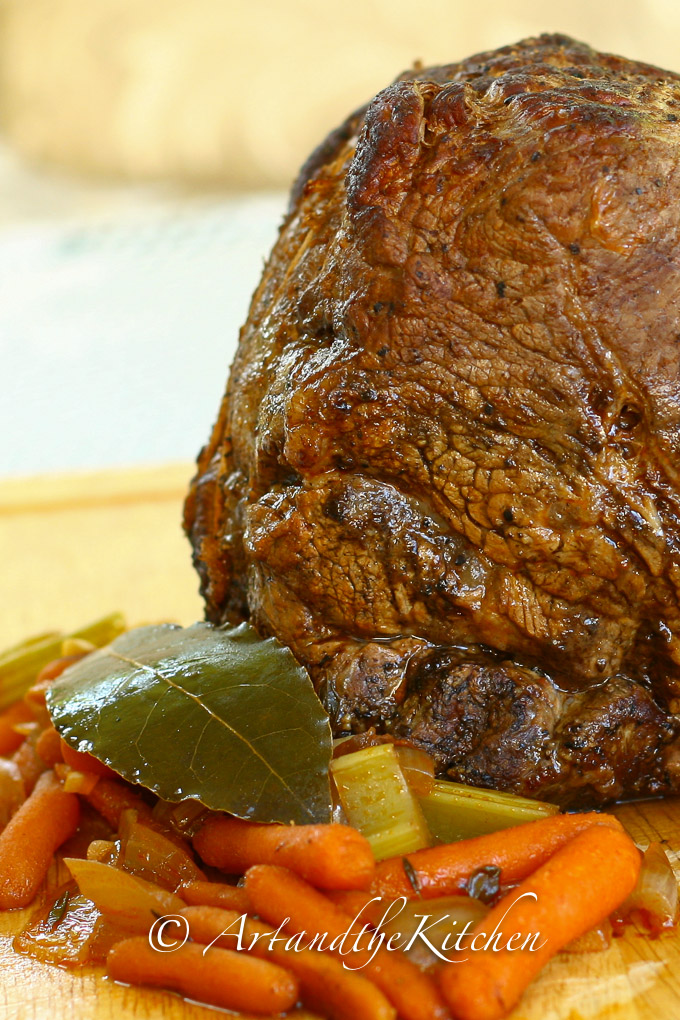 Roast beef vegetables and herbs on wood cutting board.