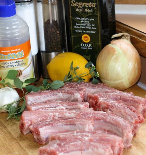 Chopped baby back ribs, honey, onion, lemon, fresh oregano and olive oil on wood tray.