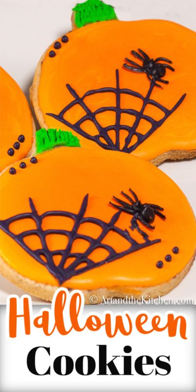 Pumpkin shaped sugar cookies decorated with orange icing and black spider web.