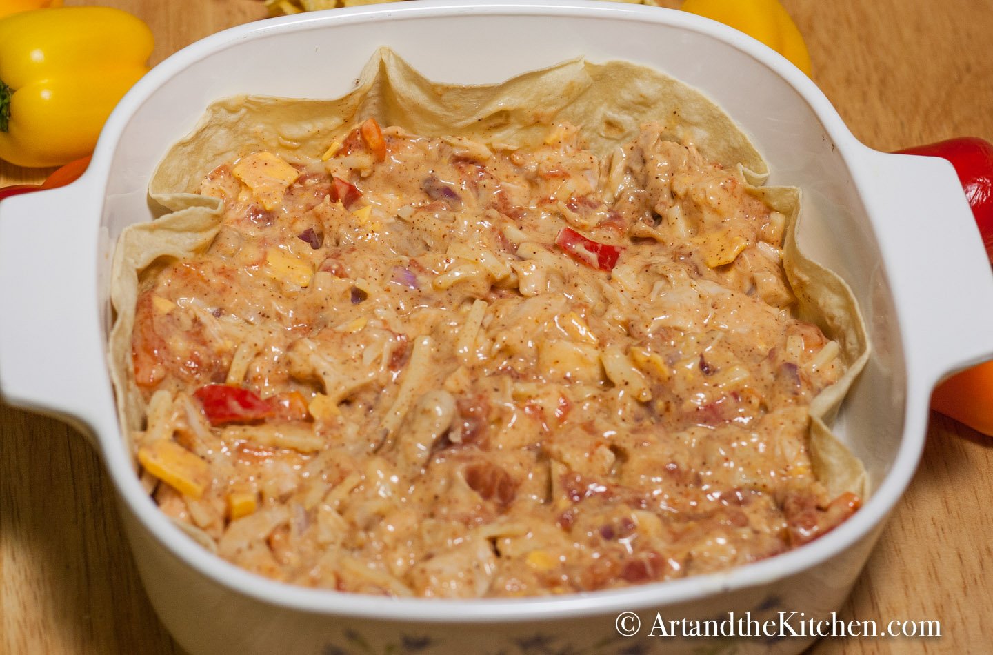 Square casserole dish filled with layer of flour tortillas and turkey enchilada mix.