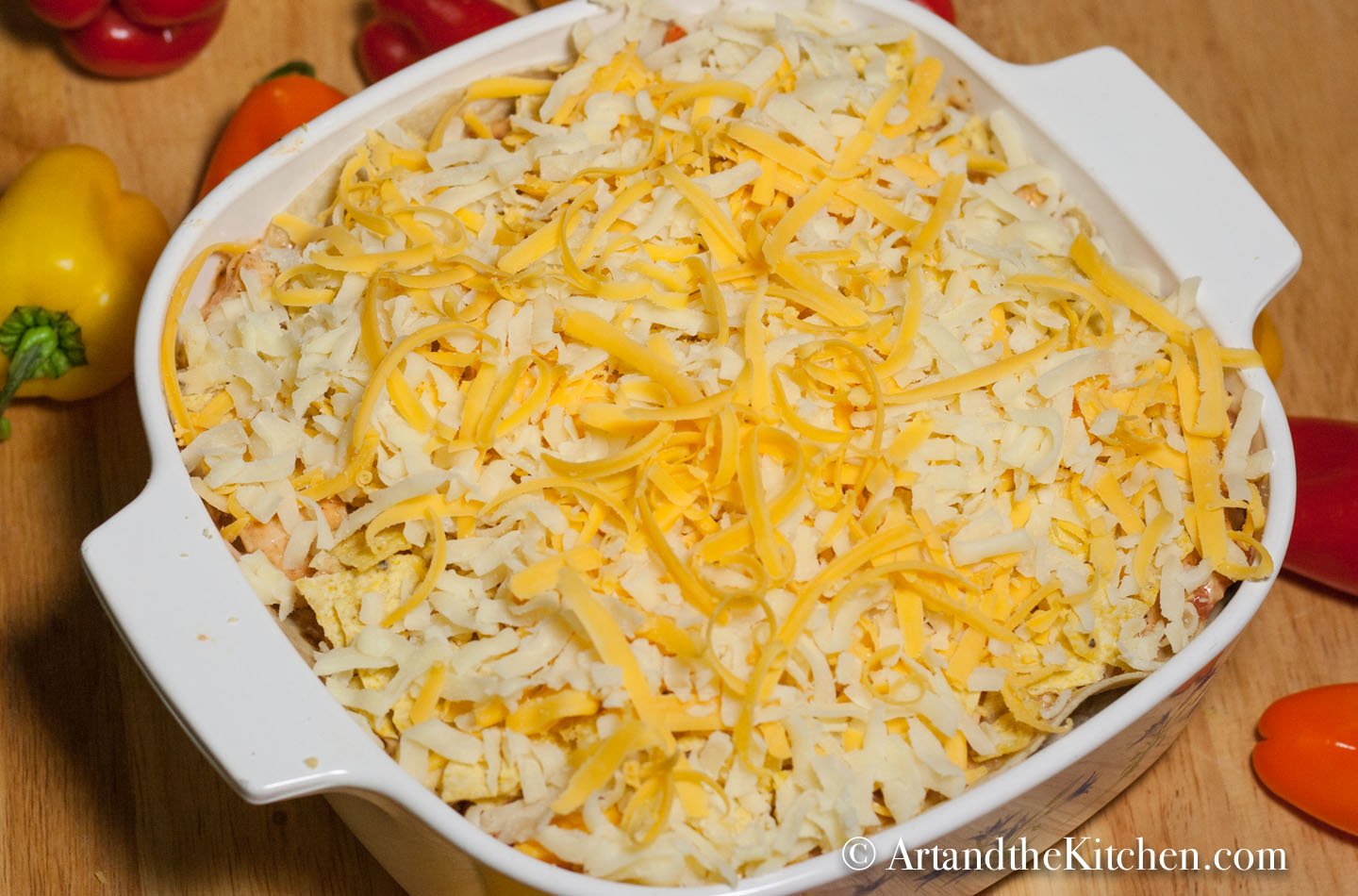 Square casserole dish filled with layers of tortillas, enchilada mix, then topped with shredded cheese.