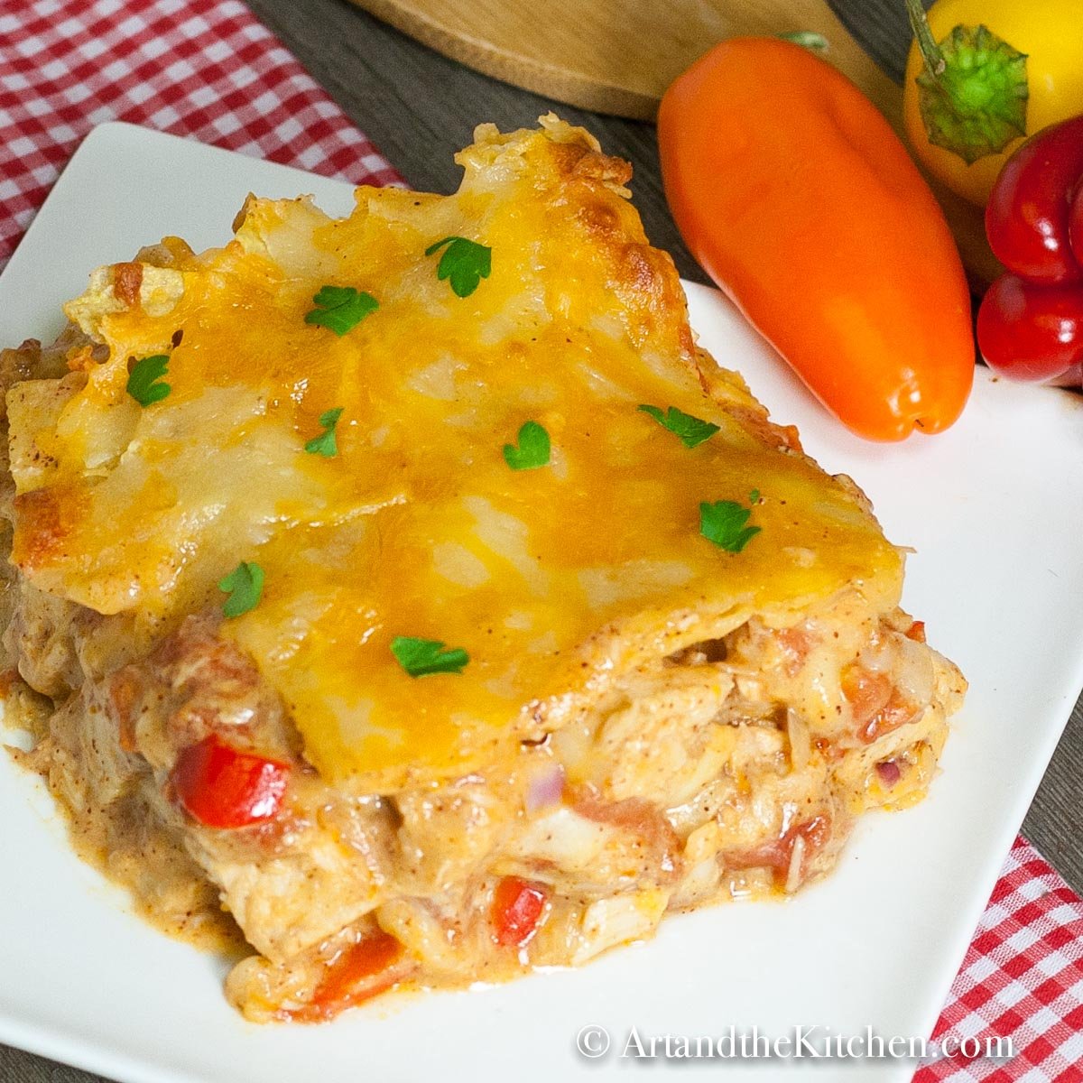 Slice of casserole on a white plate on top of a checkered napkin.