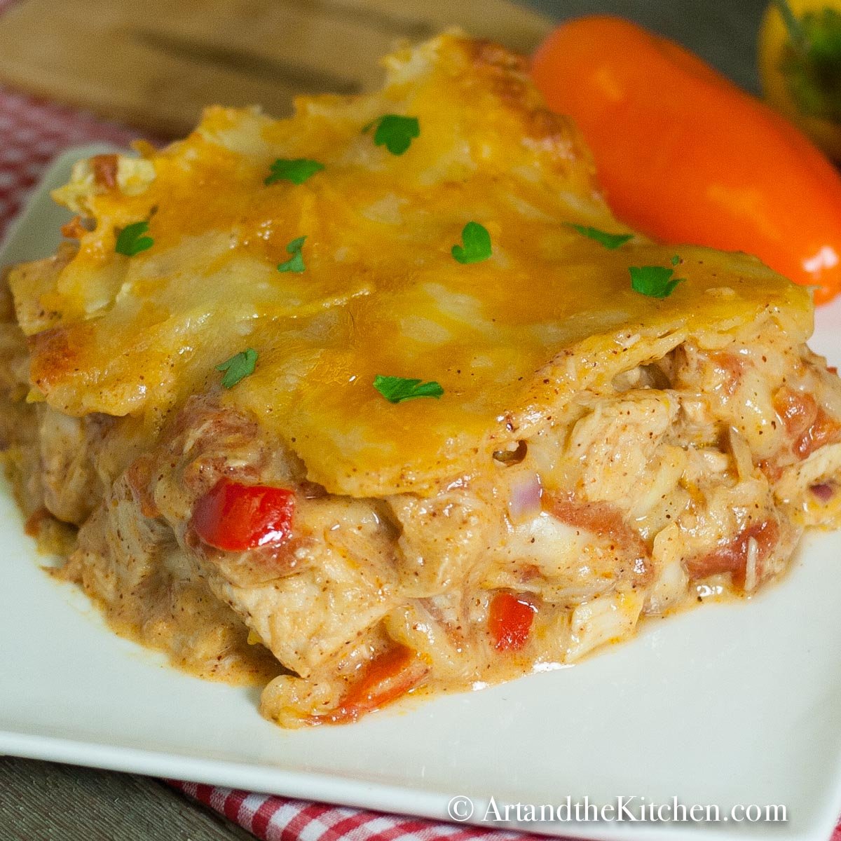 Slice of casserole on a white plate on top of a checkered napkin.