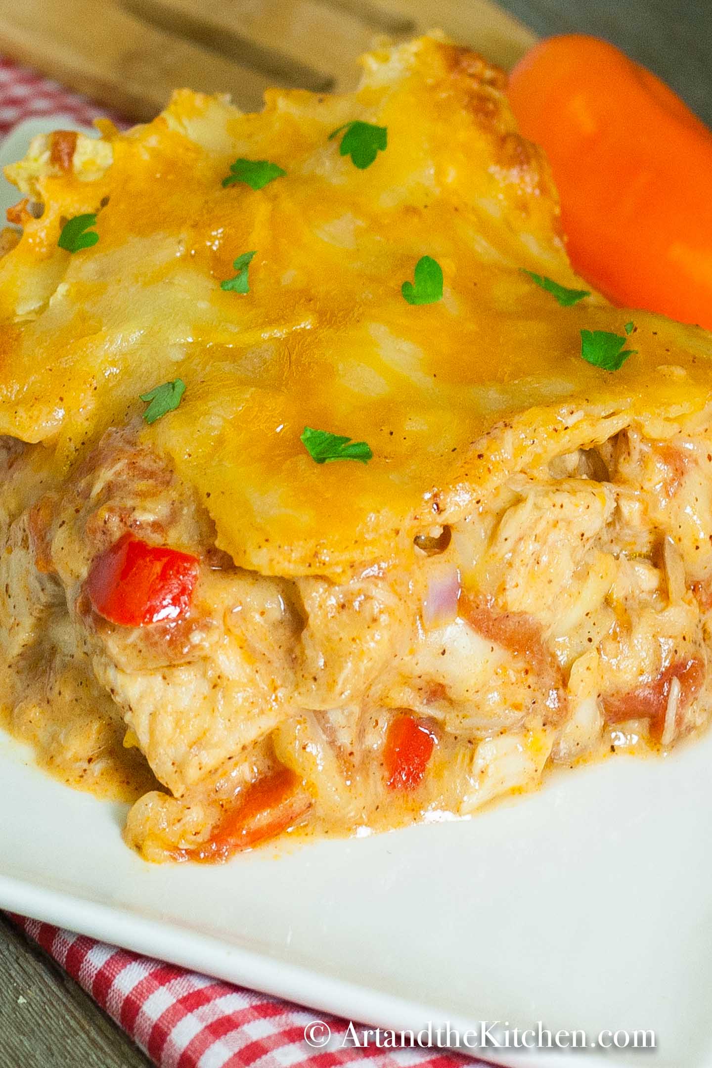 Slice of casserole on a white plate on top of a checkered napkin.