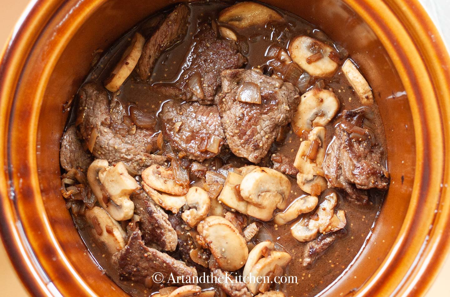 Seared beef, mushrooms in red wine broth in a slow cooker.