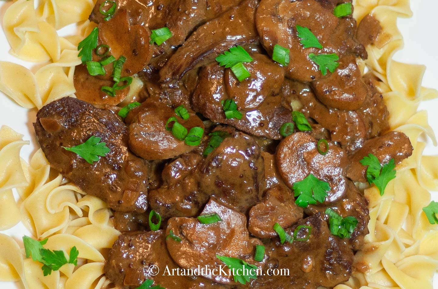 Plate of broad noodles topped with beef stroganoff.