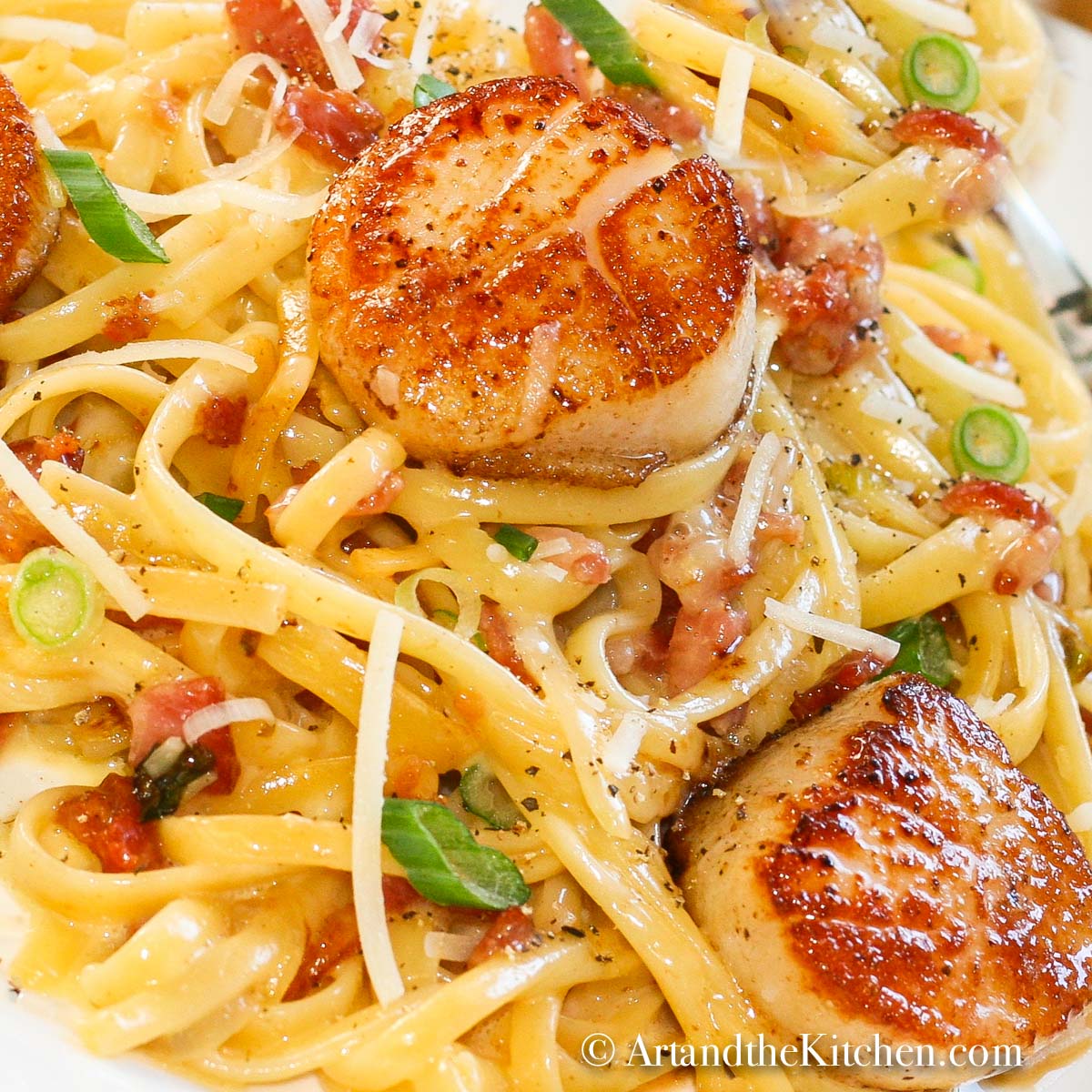 Plate of linguine pasta topped with seared scallops, tossed in carbonara sauce.