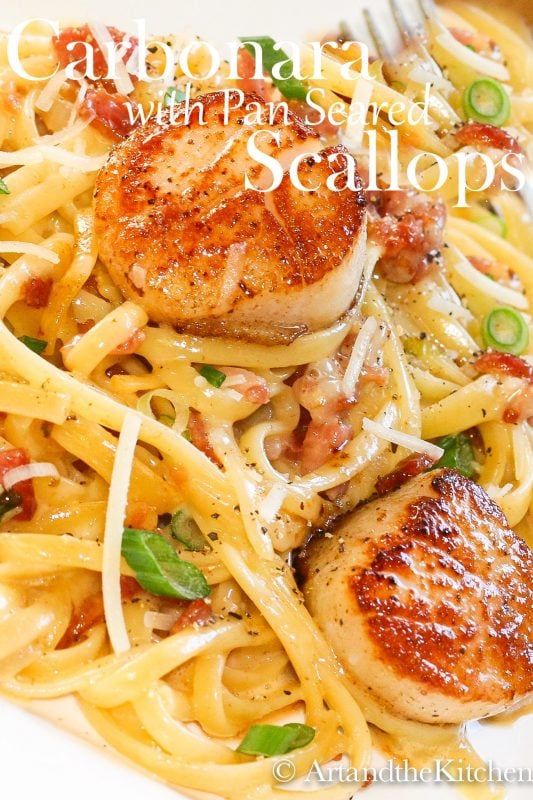 linguine pasta in a creamy carbonara sauce topped with pan seared scallops and green onion slices
