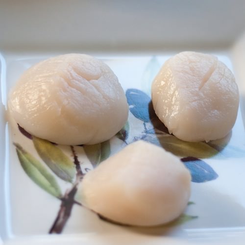 three raw scallops on decorative plate