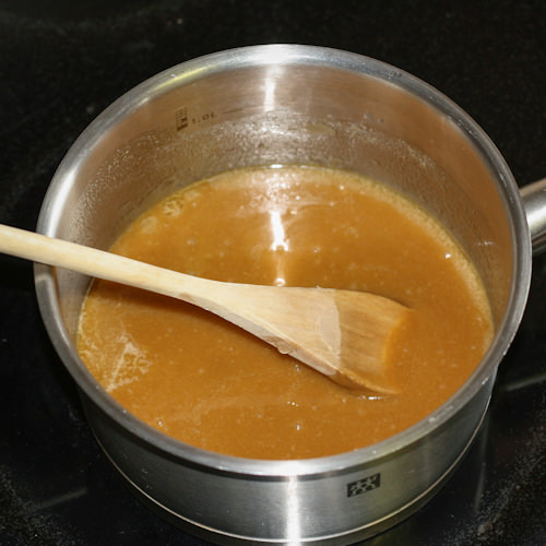 Caramel sauce cooking in stainless steel pot.