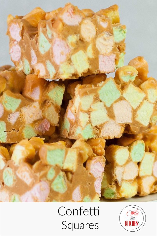 Squares made with colored mini marshmallows and peanuts butter, stacked on a plate.