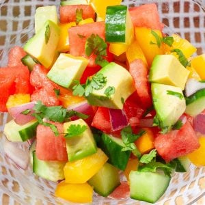 Colorful salad of cubed watermelon, cucumber, avocado, yellow peppers and cilantro.