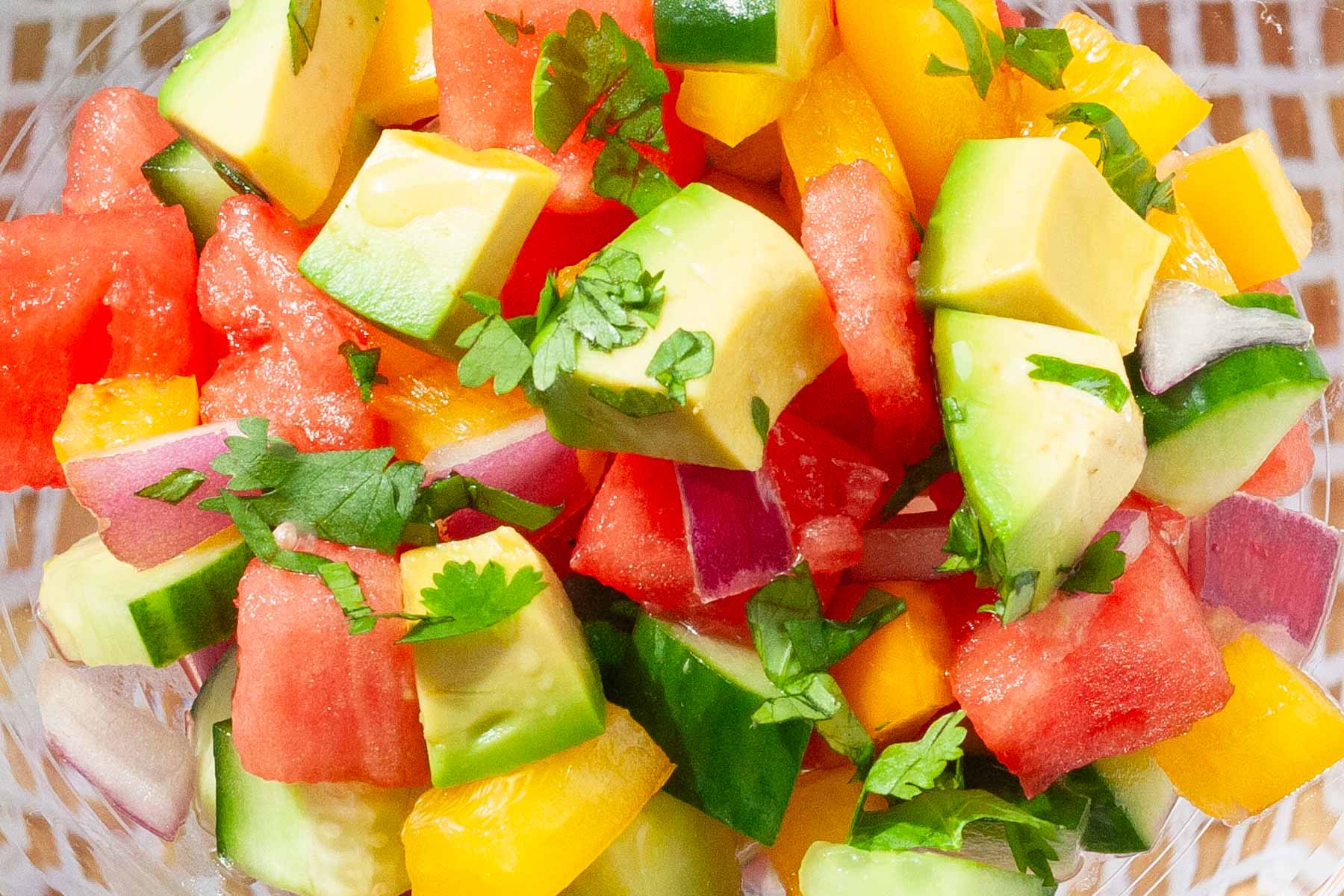 Colorful salad of cucumber, watermelon, avocado, yellow peppers and cilantro.