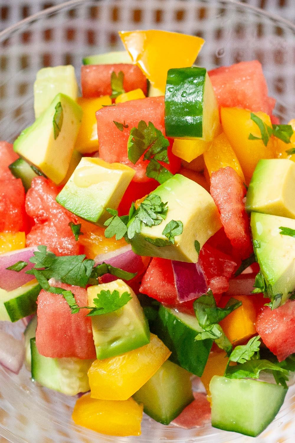 Colorful salad of cucumber, watermelon, avocado, yellow peppers and cilantro.