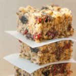 Stack of three homemade protein bars separated with parchment paper loaded with seeds and dry fruit