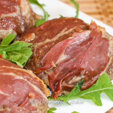 Beef burgers covered with a layer of prosciutto.