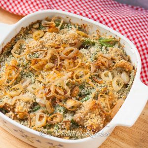 Square baking dish filled with green bean casserole topped with crunchy shallots.