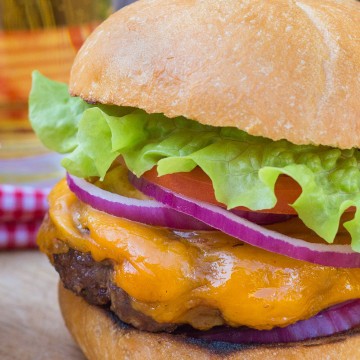 Homemade cheeseburger with slices of red onion, tomato and lettuce.