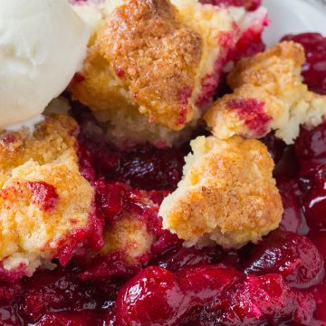 Plate of sour cherry cobbler topped with scoop of ice cream.