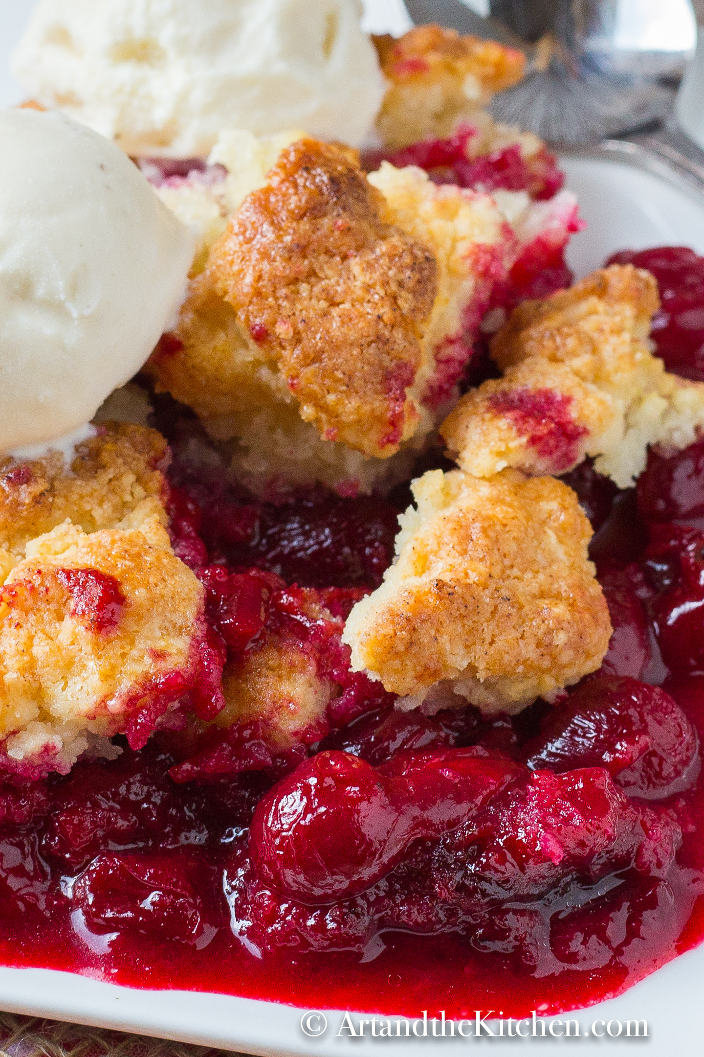 Plate of sour cherry cobbler topped with scoop of ice cream.