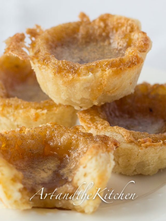 Stack of four butter tarts on white plate.