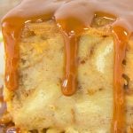 Bread pudding square drenched in creamy caramel sauce sits on a floral plate.