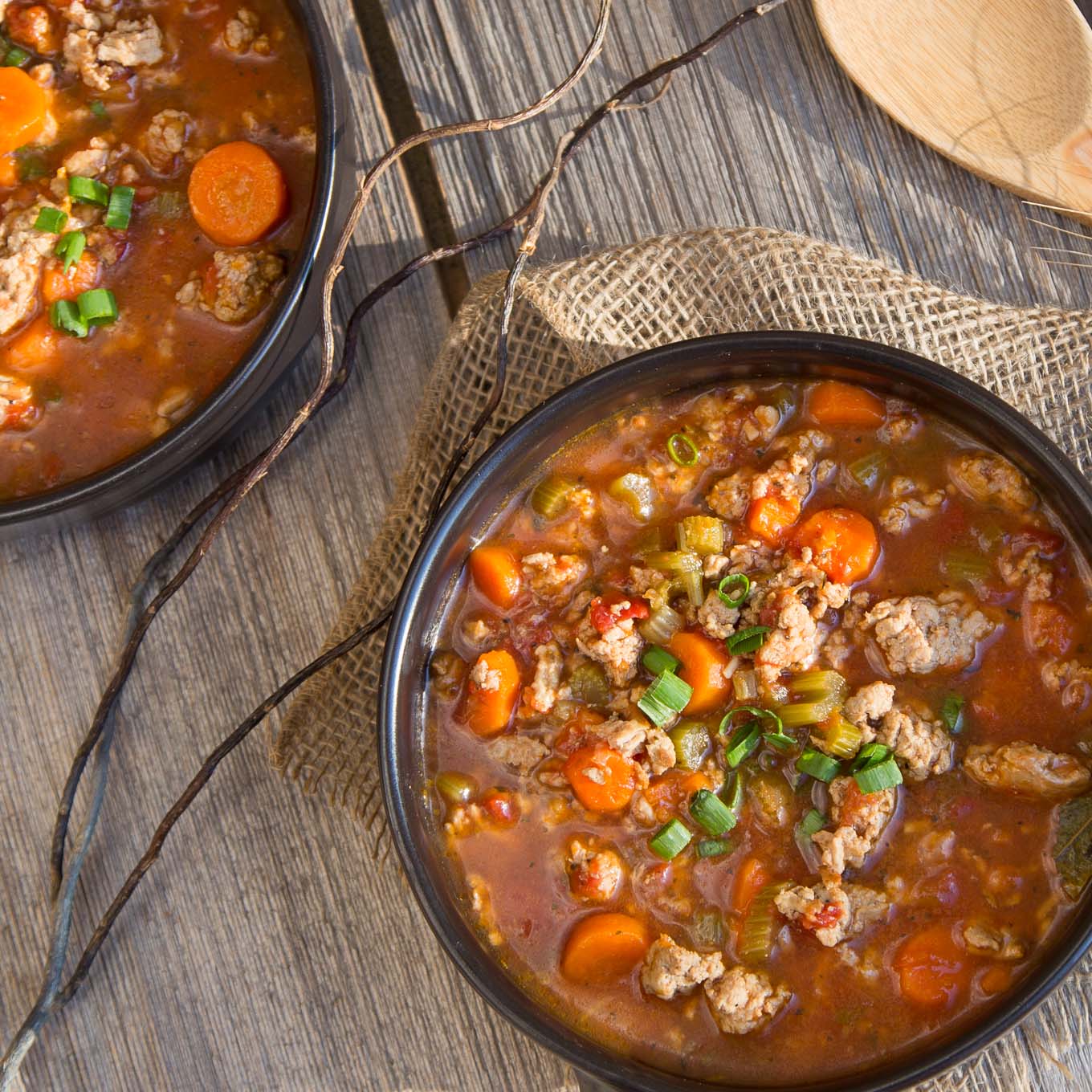 soup with chunks of ground turkey, vegetables simmered in a tomato beef broth served in a black bowl