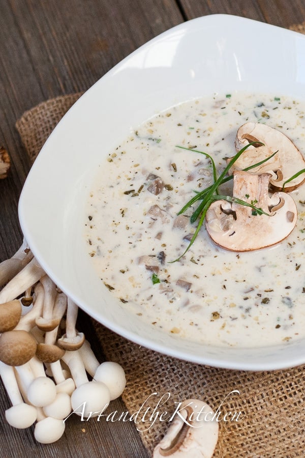 Homemade mushroom soup served in a white bowl garnished with fresh mushrooms and chives
