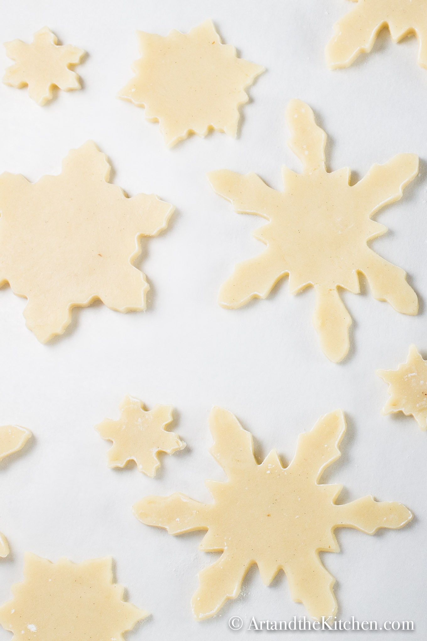 White parchment line baking pan filled with holiday shaped unbaked cookies.