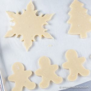 White parchment line baking pan filled with holiday shaped unbaked cookies.